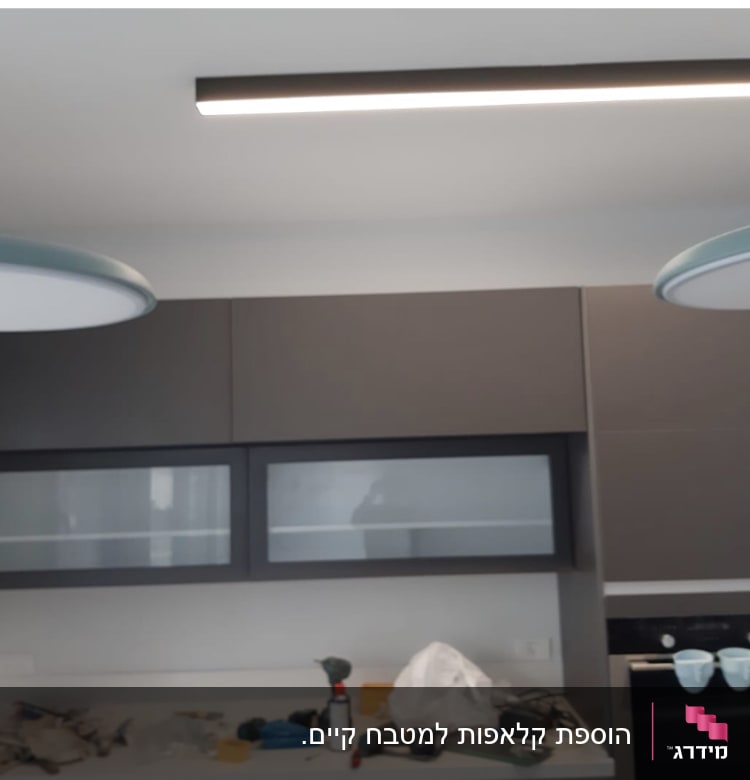 מטבח עם ארונות כהים, כלים על השיש